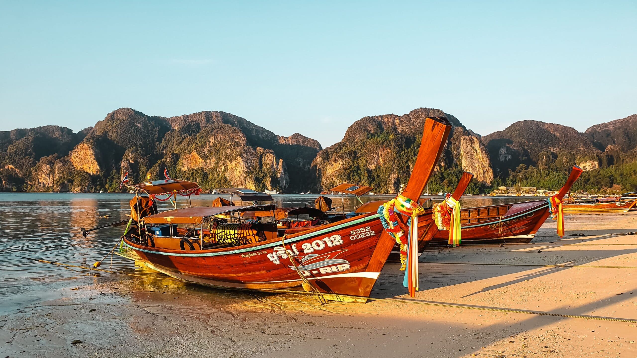 longtail boats on a tranquil Phuket beach during sunset