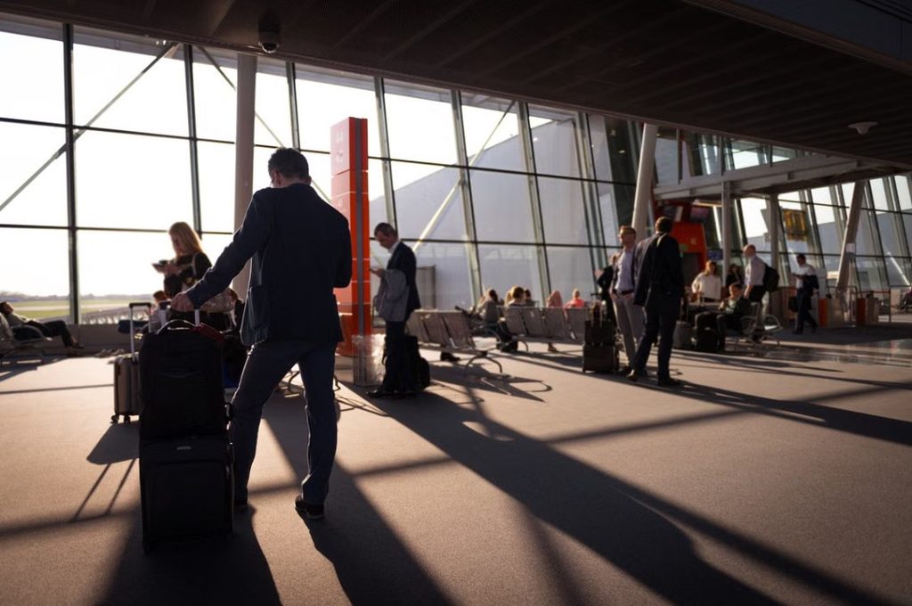 Business traveler walking through a busy airport terminal at sunset
