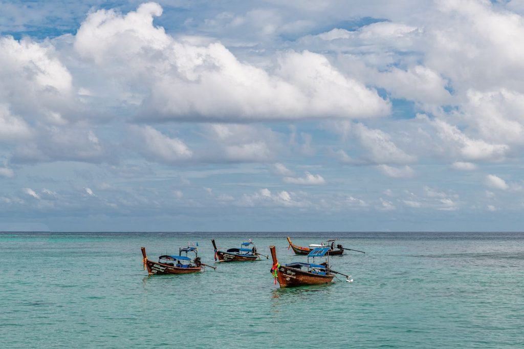 Calm west-coast Phuket beach in the dry season with a longtail boat on turquoise water