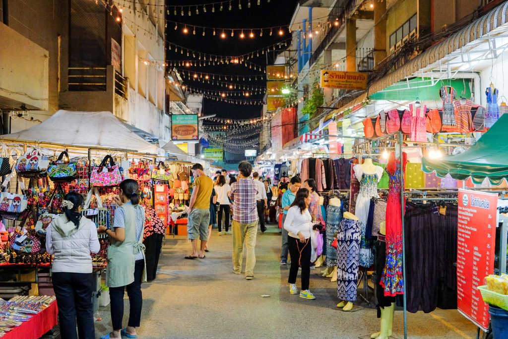 ravellers walking through a busy night market in Thailand